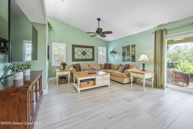 living room featuring vaulted ceiling, ceiling fan, and a healthy amount of sunlight