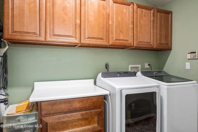 laundry room with separate washer and dryer and cabinets