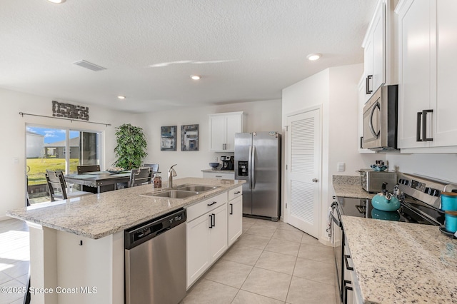 kitchen featuring stainless steel appliances, visible vents, white cabinetry, a sink, and an island with sink