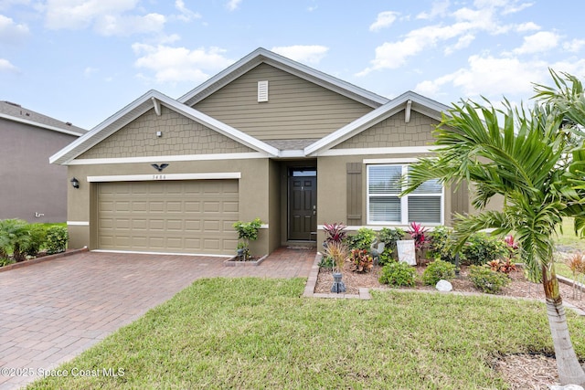 view of front of home featuring a front yard, decorative driveway, an attached garage, and stucco siding