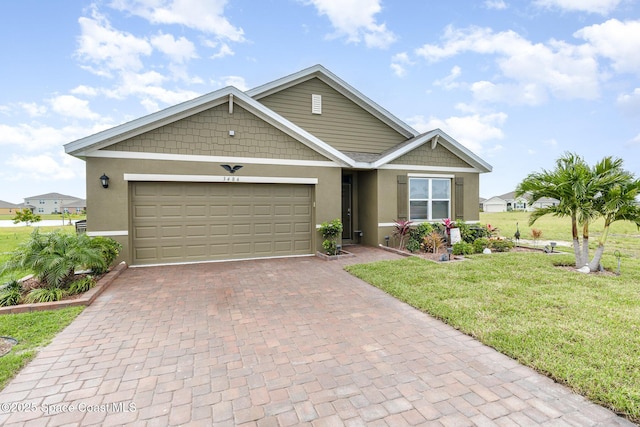 view of front facade featuring an attached garage, a front yard, decorative driveway, and stucco siding