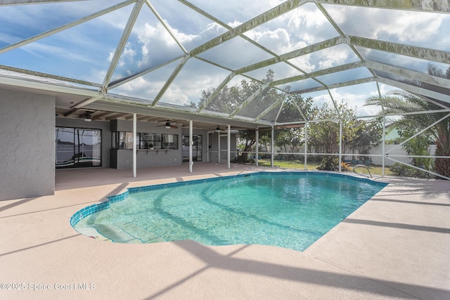 view of swimming pool with a patio, ceiling fan, and glass enclosure