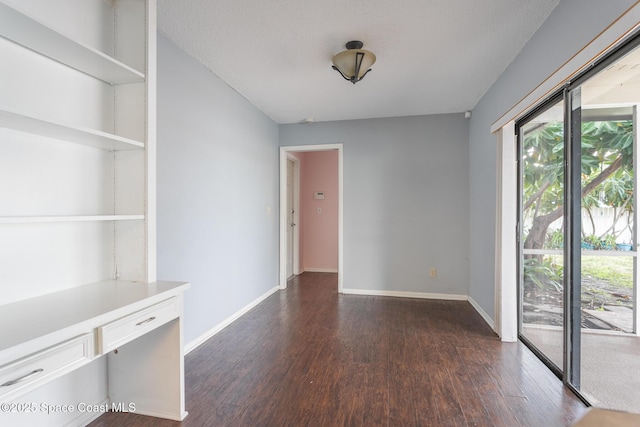 unfurnished room with dark wood-type flooring and a textured ceiling