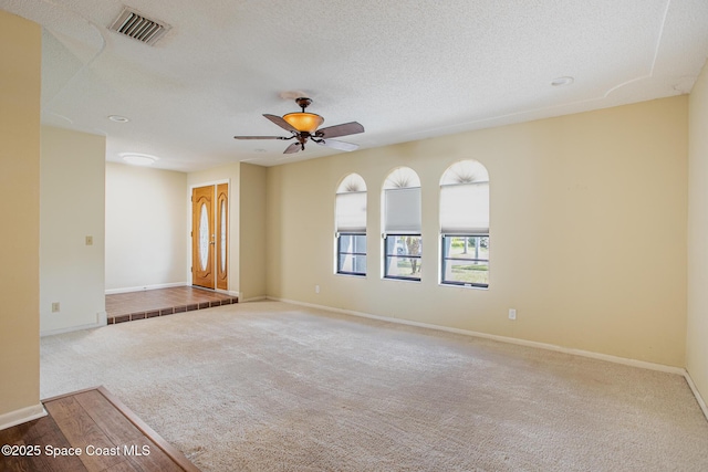 carpeted spare room with ceiling fan and a textured ceiling