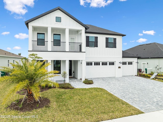 view of front of house with a garage, a balcony, and a front yard