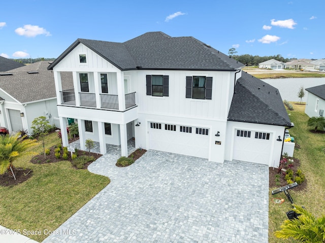 modern farmhouse featuring a front yard, a balcony, and a garage