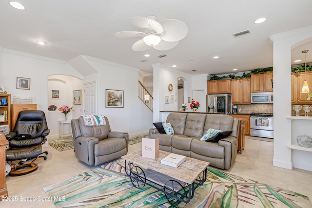 tiled living room with ceiling fan and crown molding