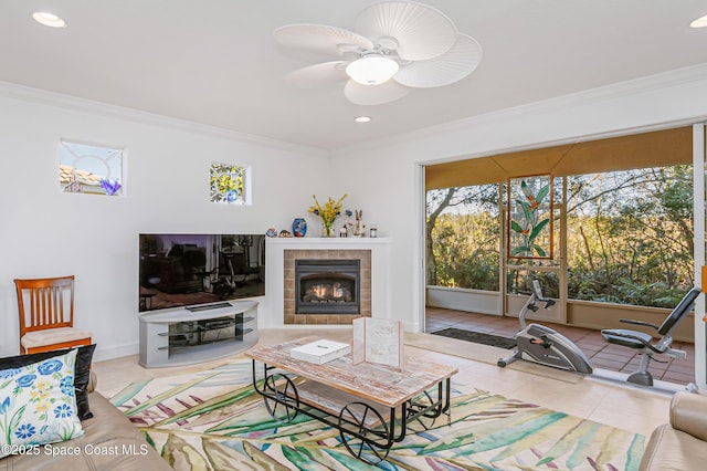 tiled living room with a tile fireplace, ceiling fan, and ornamental molding