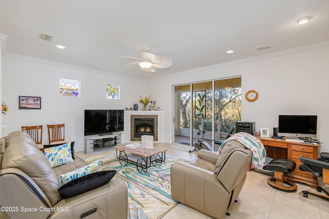 tiled living room featuring ceiling fan, a fireplace, and ornamental molding