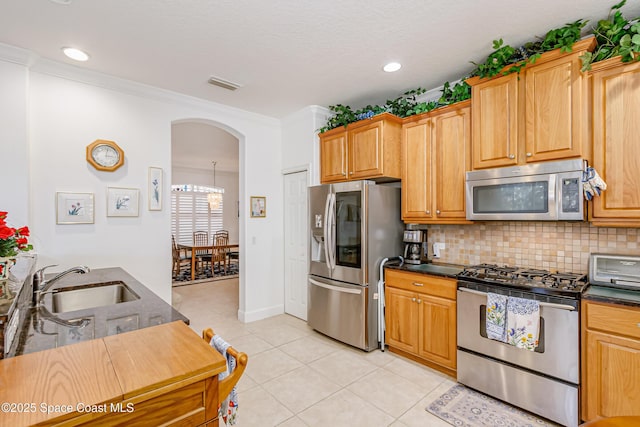 kitchen featuring sink, appliances with stainless steel finishes, decorative backsplash, light tile patterned floors, and ornamental molding