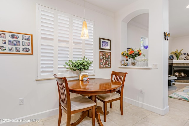 tiled dining space featuring ornamental molding and a tiled fireplace