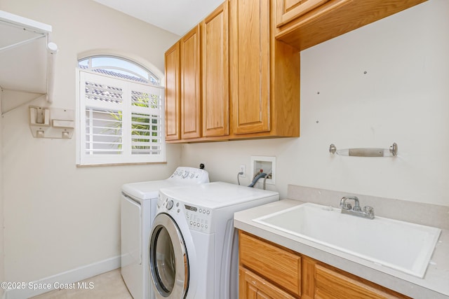 laundry area featuring washer and clothes dryer, sink, light tile patterned floors, and cabinets