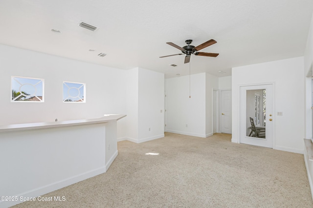 unfurnished living room featuring ceiling fan and light carpet