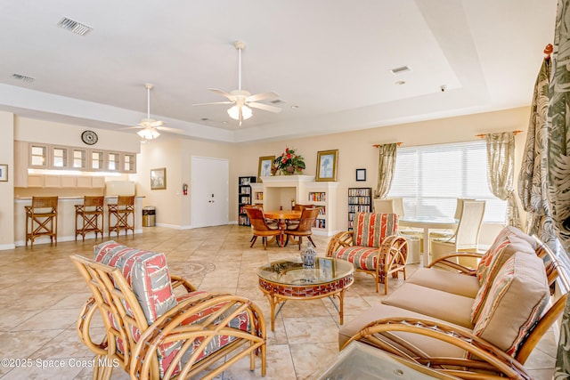 tiled living room featuring a tray ceiling and ceiling fan