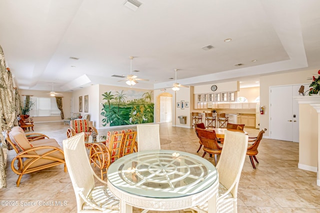 tiled dining area with a raised ceiling and ceiling fan