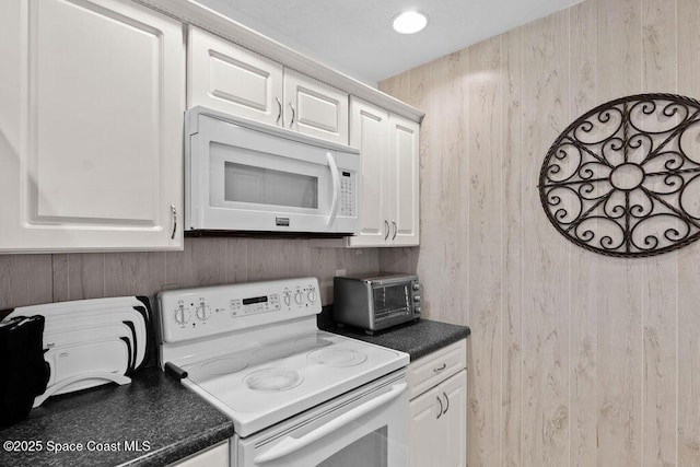 kitchen with white cabinets, white appliances, and wooden walls