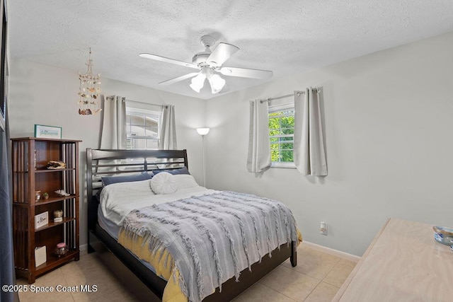 tiled bedroom with ceiling fan and a textured ceiling