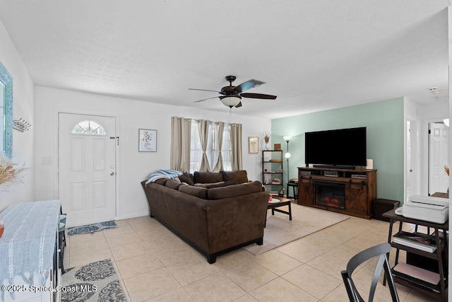 tiled living room featuring a textured ceiling, ceiling fan, a fireplace, and a wealth of natural light