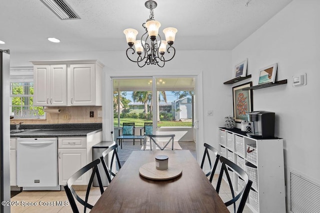 dining room with a textured ceiling, a notable chandelier, and light tile patterned flooring