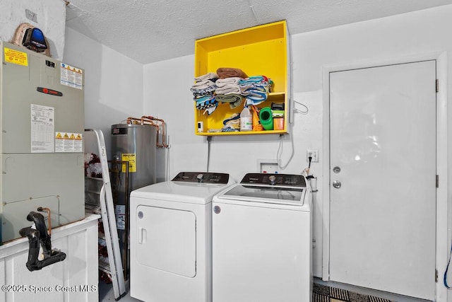 laundry area with heating unit, gas water heater, washer and clothes dryer, and a textured ceiling