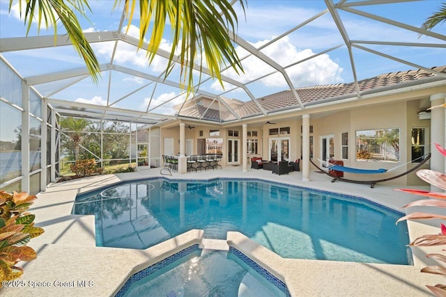 view of swimming pool with ceiling fan, a patio, a pool with connected hot tub, an outdoor living space, and french doors