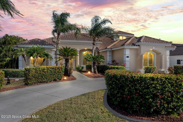 mediterranean / spanish home featuring a tiled roof and stucco siding