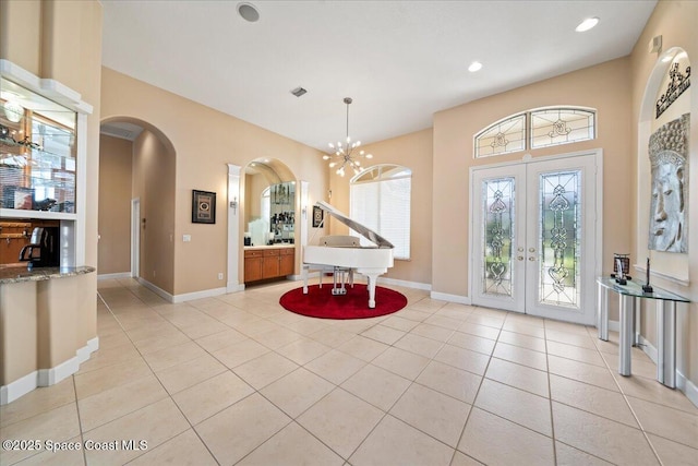 entrance foyer with an inviting chandelier, light tile patterned floors, and french doors