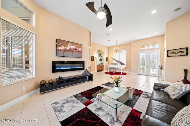 tiled living room with ceiling fan with notable chandelier and french doors