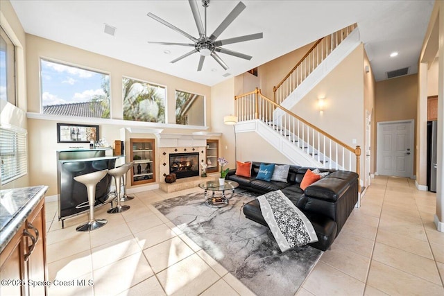 living room with a tile fireplace, ceiling fan, and light tile patterned flooring