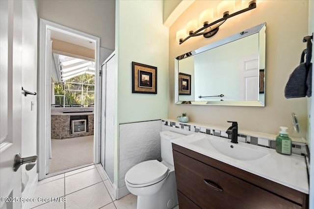 bathroom featuring tile patterned flooring, vanity, toilet, and tile walls