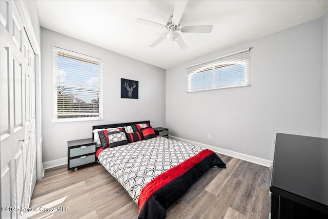 bedroom featuring a ceiling fan, a closet, baseboards, and wood finished floors