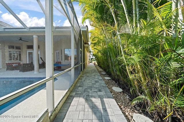 view of side of property featuring ceiling fan, a lanai, and a patio