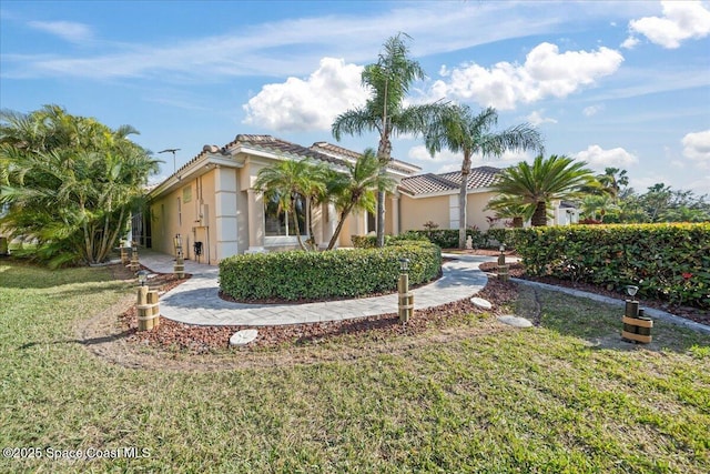 view of front facade featuring a tile roof, a front lawn, and stucco siding