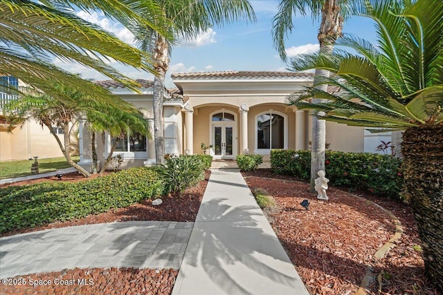 view of front of property with stucco siding, a tile roof, and french doors