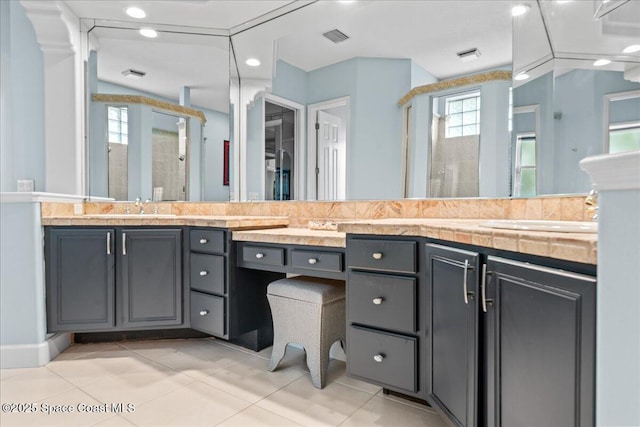 full bathroom with double vanity, a stall shower, a sink, and tile patterned floors