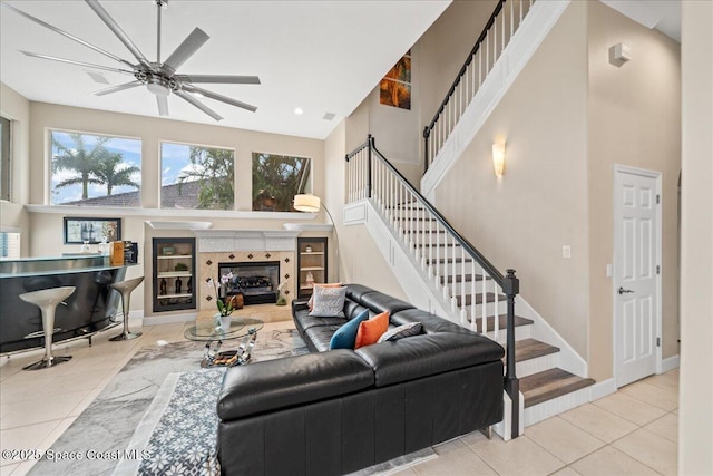 tiled living room featuring a tiled fireplace, a high ceiling, and stairs