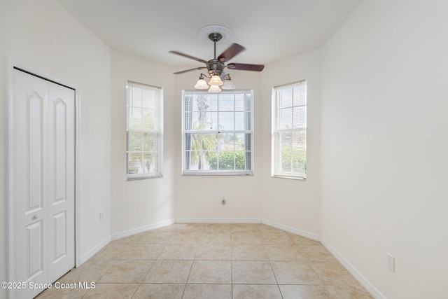 empty room with ceiling fan and light tile patterned floors