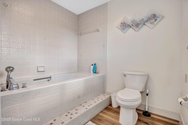 bathroom featuring hardwood / wood-style flooring, toilet, and a relaxing tiled tub