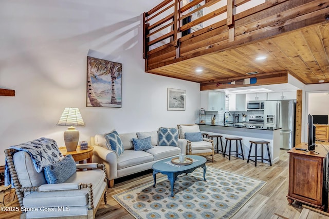 living room featuring beam ceiling, sink, wood ceiling, and light hardwood / wood-style floors