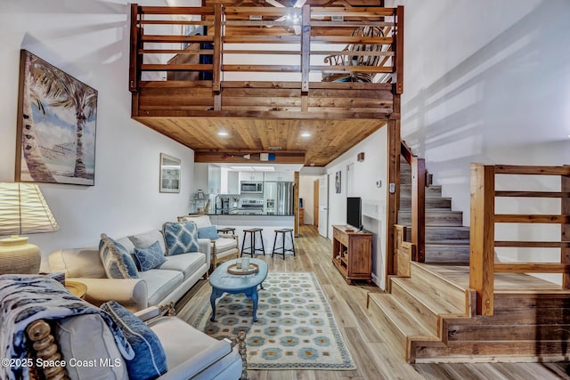 living room with light wood-type flooring, wooden ceiling, sink, and a high ceiling