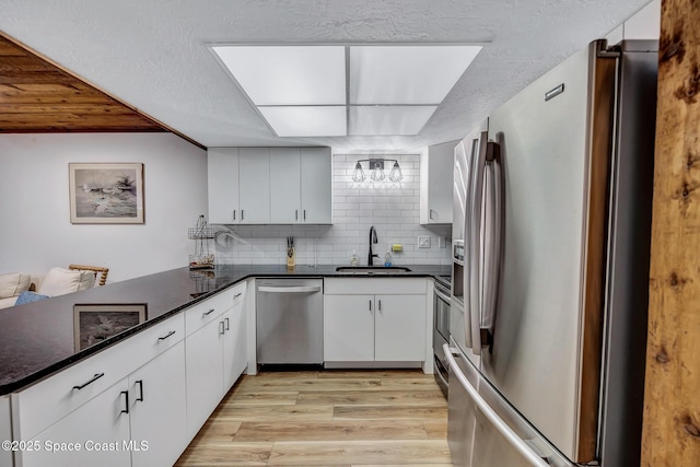 kitchen featuring kitchen peninsula, sink, white cabinets, and appliances with stainless steel finishes