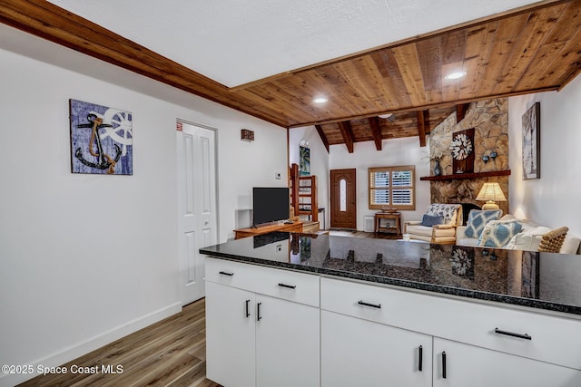 kitchen with white cabinets, dark hardwood / wood-style floors, dark stone countertops, and wood ceiling