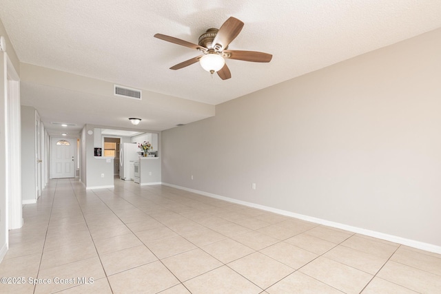 tiled empty room with ceiling fan and a textured ceiling