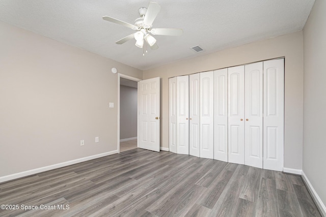 unfurnished bedroom featuring hardwood / wood-style floors, a textured ceiling, ceiling fan, and a closet