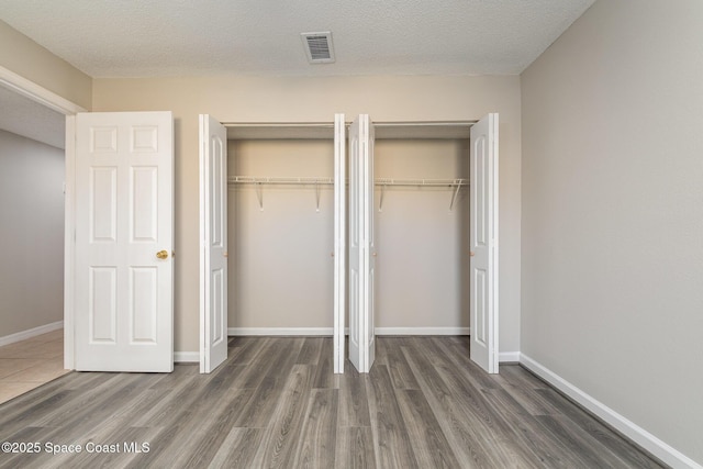 unfurnished bedroom with dark hardwood / wood-style flooring and a textured ceiling