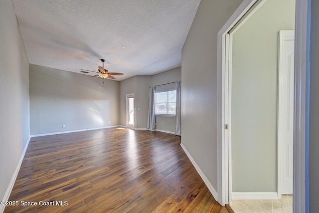 unfurnished room featuring ceiling fan, dark wood-type flooring, and a textured ceiling