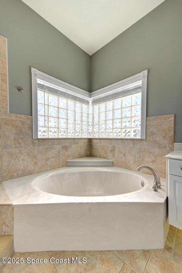 bathroom with a washtub, vanity, and tile patterned flooring