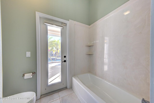 bathroom with tile patterned flooring, toilet, and a washtub