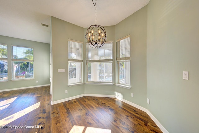 unfurnished dining area featuring dark hardwood / wood-style flooring, a wealth of natural light, and an inviting chandelier