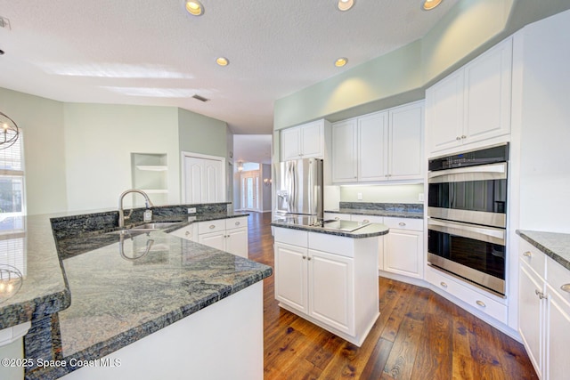 kitchen with white cabinetry, sink, dark stone counters, a kitchen island, and appliances with stainless steel finishes